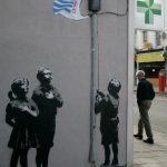 A man walks past artwork showing children raising a plastic bag from British supermarket chain Tesco as a flag by artist Banksy on a wall in London. Photo: Akira Suemori/AP