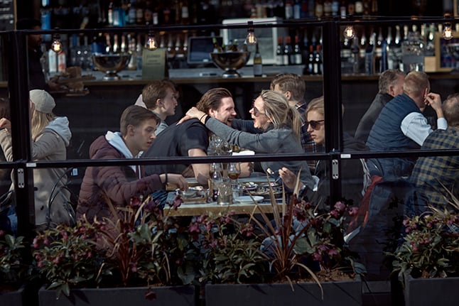 A couple hug and laugh as they have lunch in a restaurant in Stockholm,  just as the pandemic begins in April 2020. 