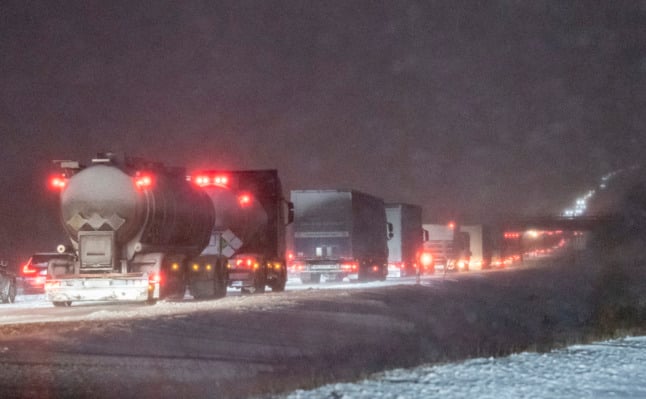lorries queuing in the dark on a snowy motorway